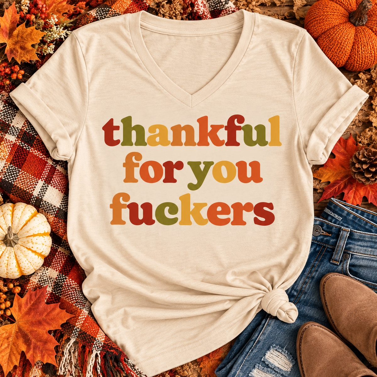 Funny Thankful for You Fuckers Thanksgiving graphic tee featuring bold retro lettering in burnt orange, mustard yellow, olive green, and rust red. Women's fall-inspired short sleeve crewneck shirt available in beige and brown, perfect for Thanksgiving and Friendsgiving.