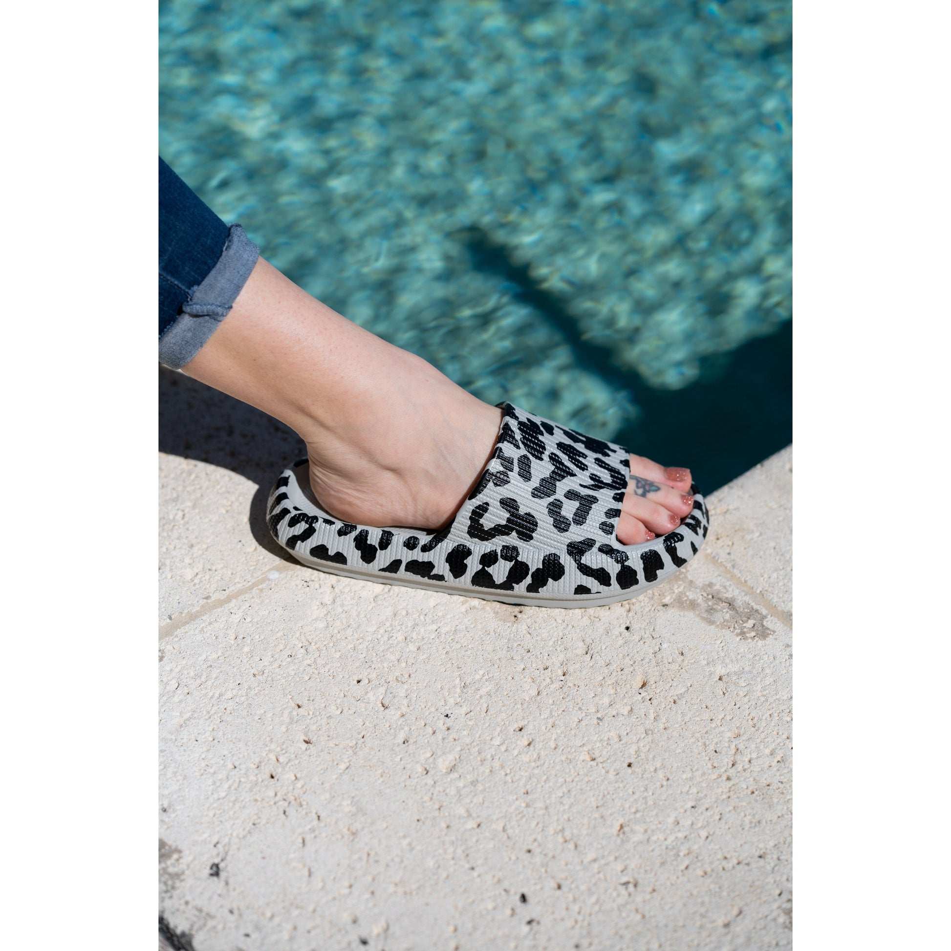 Gray leopard-print beach slides with a bold spotted pattern and easy slip-on design.