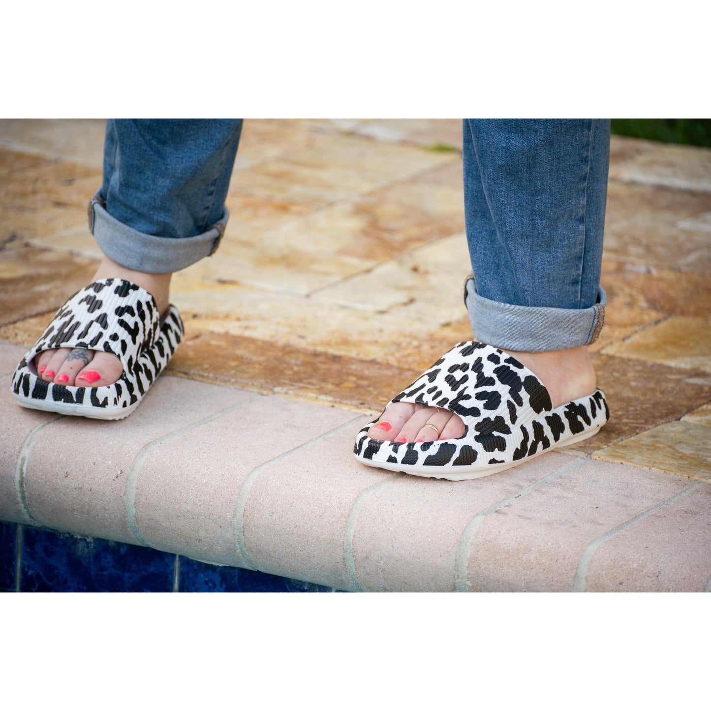 White leopard-print beach slides with a bold spotted pattern and easy slip-on design