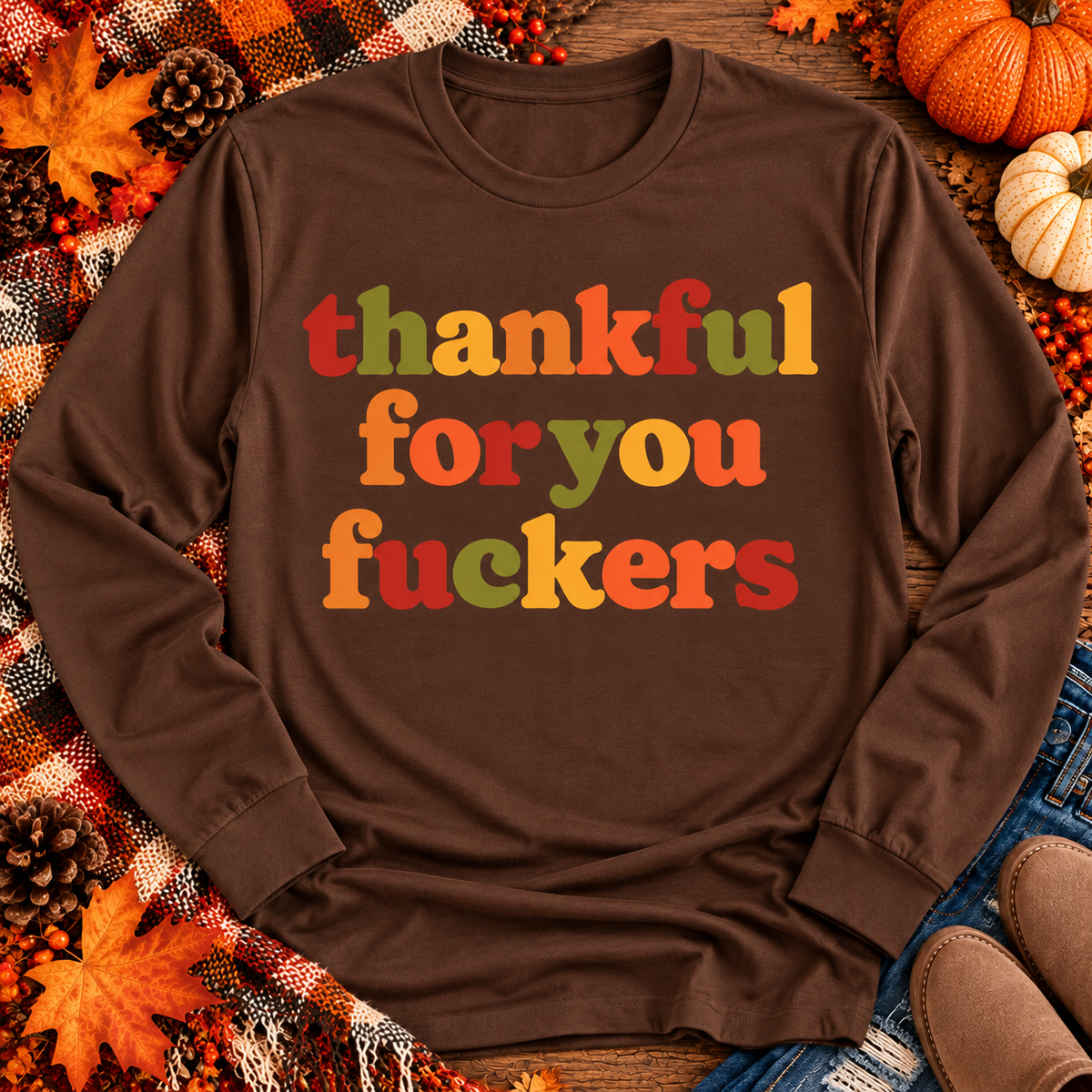 Funny Thankful for You Fuckers Thanksgiving graphic tee featuring bold retro lettering in burnt orange, mustard yellow, olive green, and rust red. Women's fall-inspired short sleeve crewneck shirt available in beige and brown, perfect for Thanksgiving and Friendsgiving.